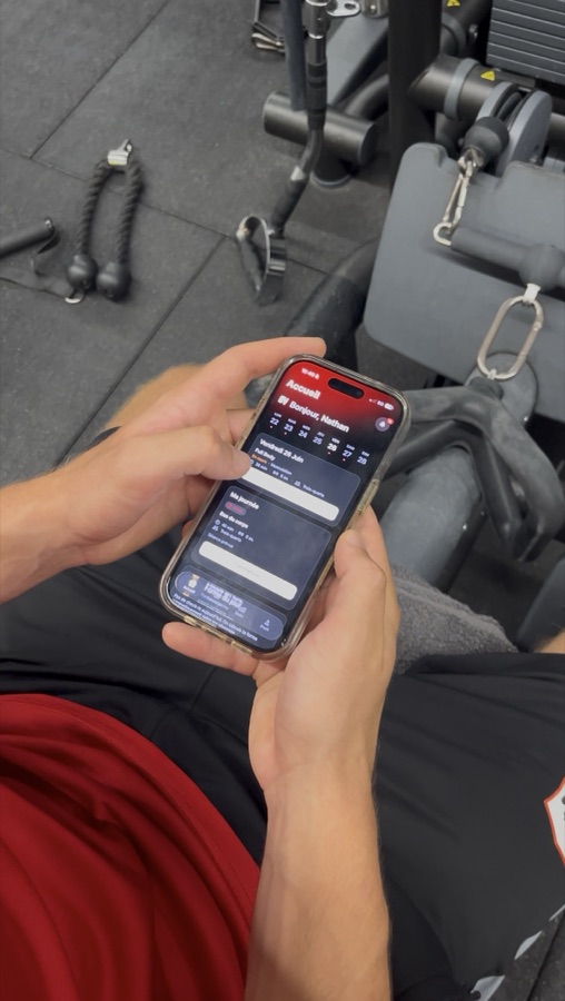 Joueur consultant l'application O'VAL sur son téléphone en salle de musculation